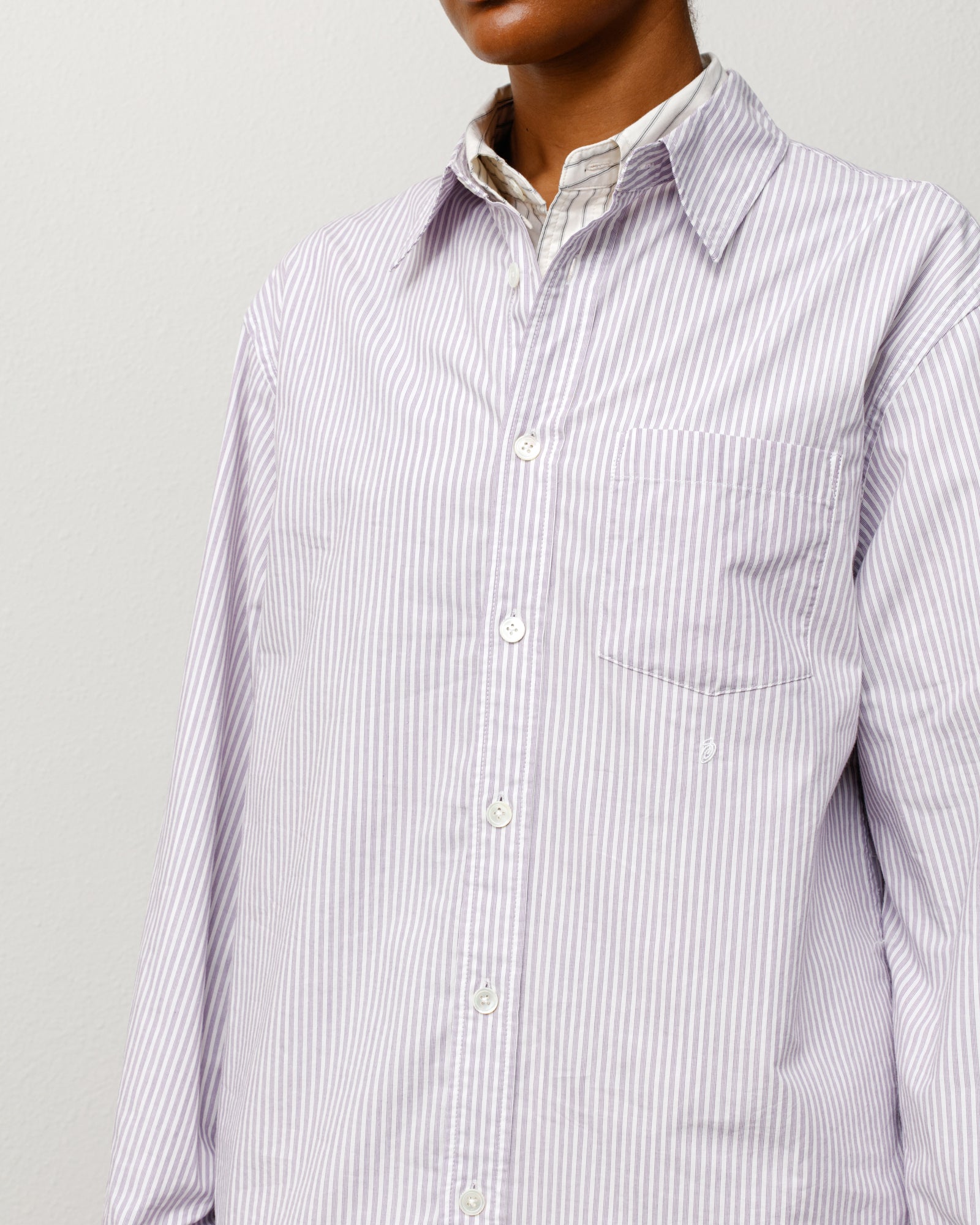 Purple striped unisex long-sleeve button-up with chest pocket, shown on model.