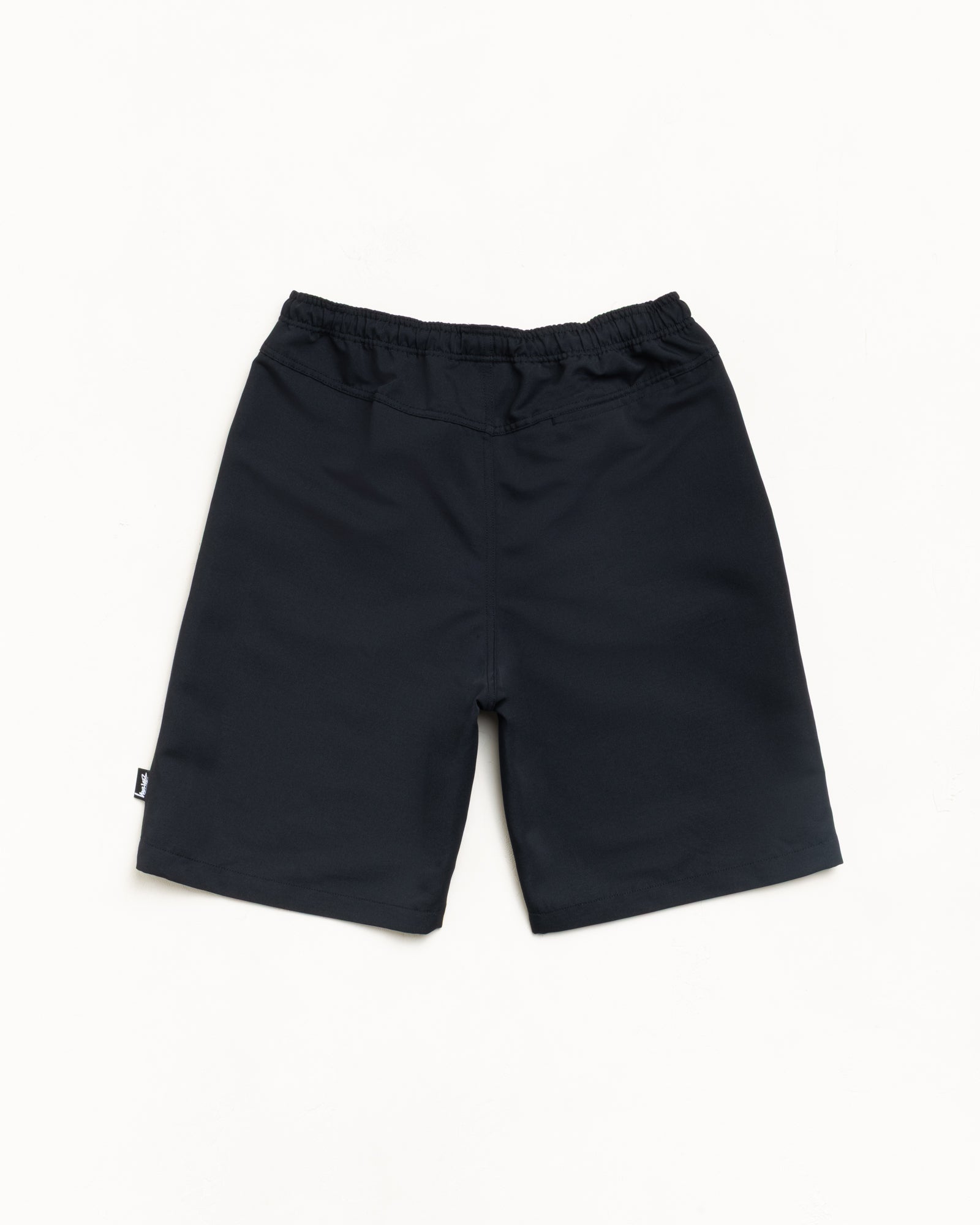 Black baggy beach shorts, back view with elastic waist and Stüssy side flag label
