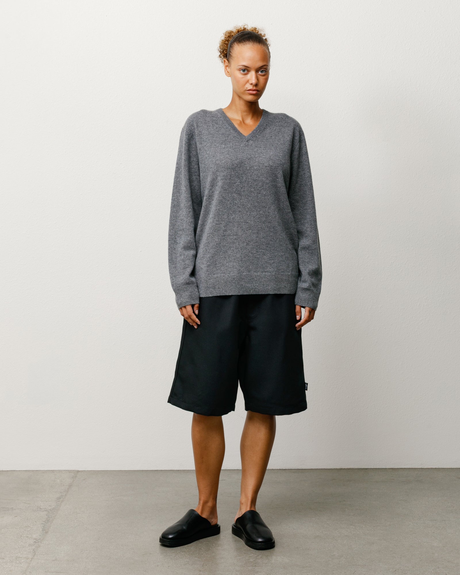 Black baggy beach shorts on model, knee-length with relaxed, unisex fit.