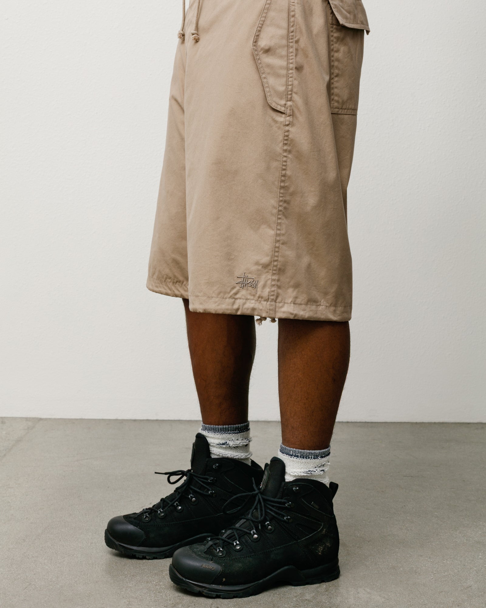 Surplus Short in khaki, baggy cotton-nylon with drawcord hem and Stüssy logo, styled with boots