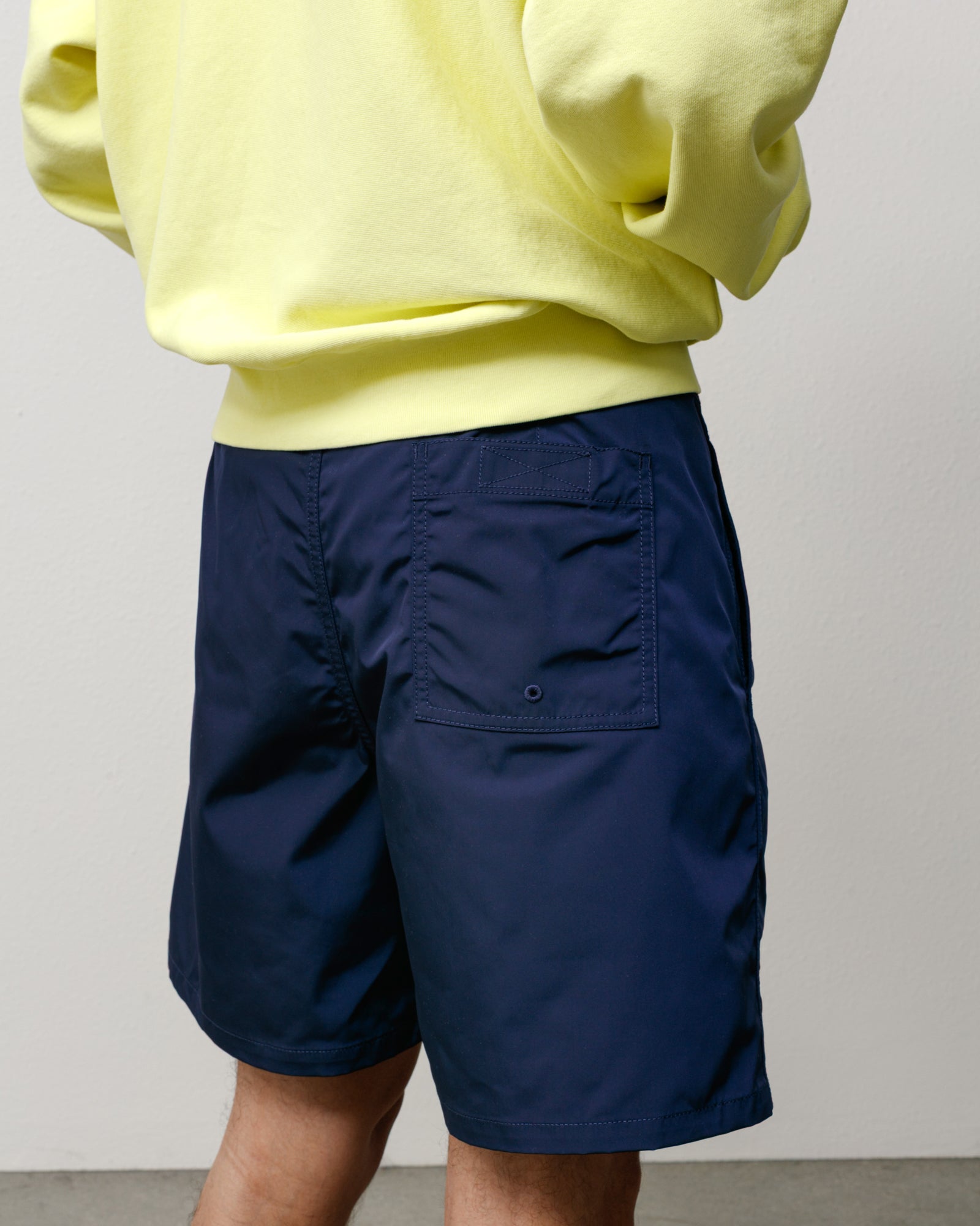 Back view of navy blue board shorts with rear patch pocket and clean, regular fit.