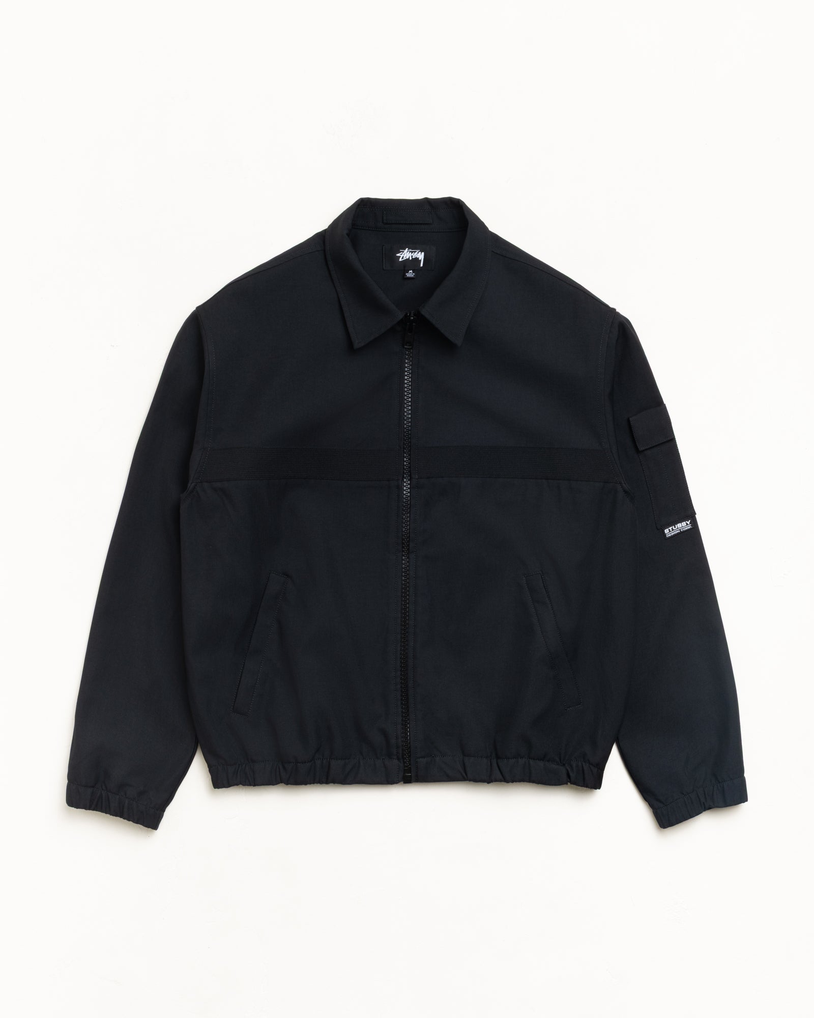 Black zip-front collared jacket with welt pockets, sleeve pocket, and elastic cuffs, laid flat.
