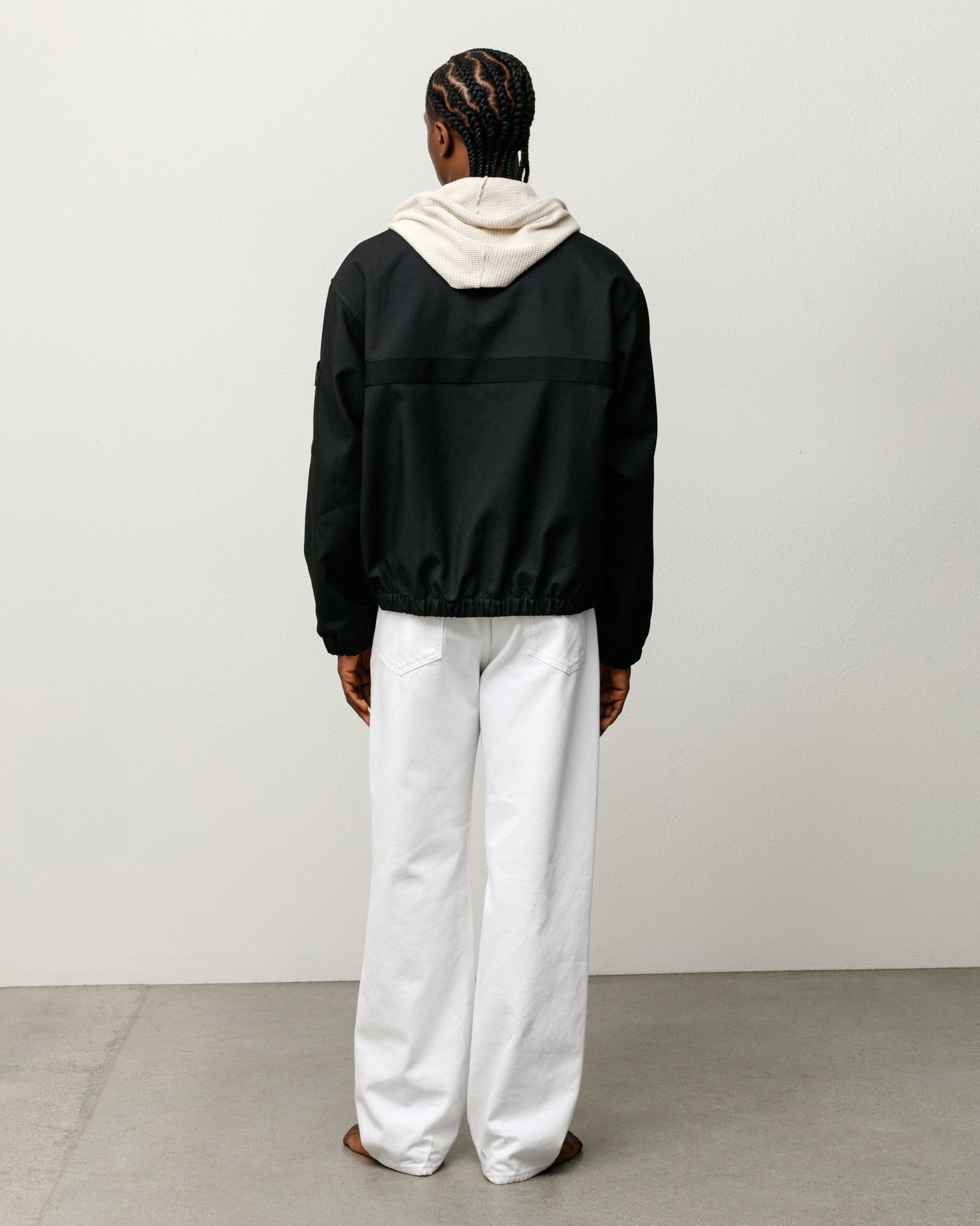 Black mechanic jacket, back view with elastic hem and boxy fit, layered over a hoodie.