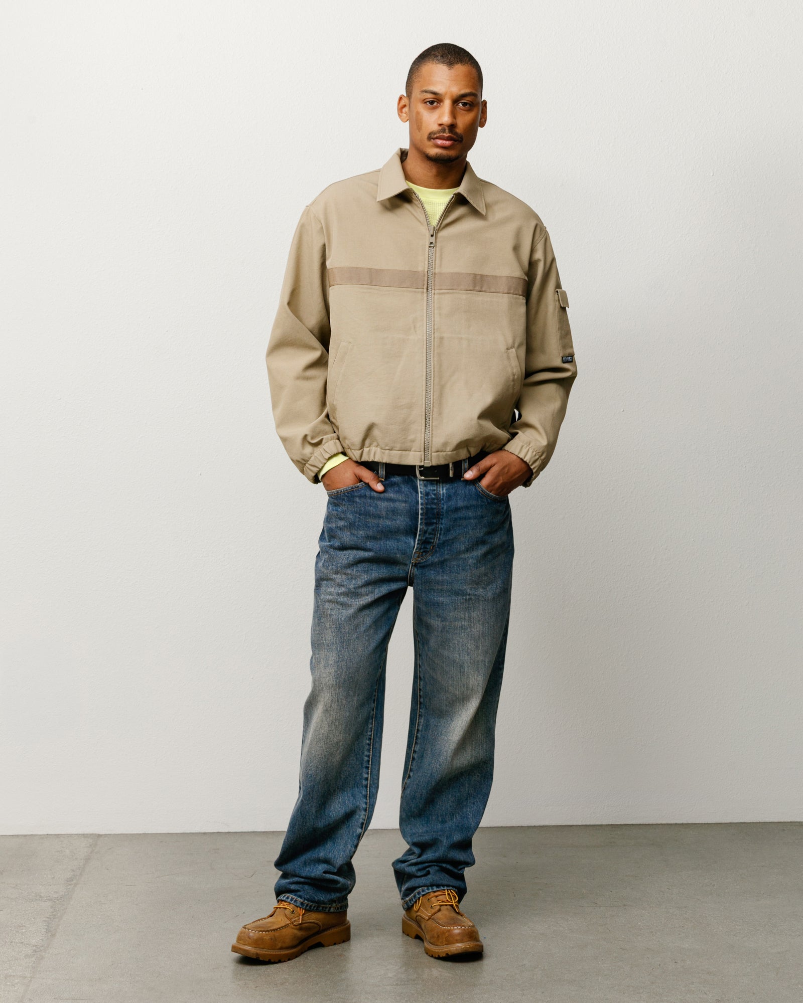 Khaki mechanic jacket on model with zip front, elastic hem, and tonal chest stripe.