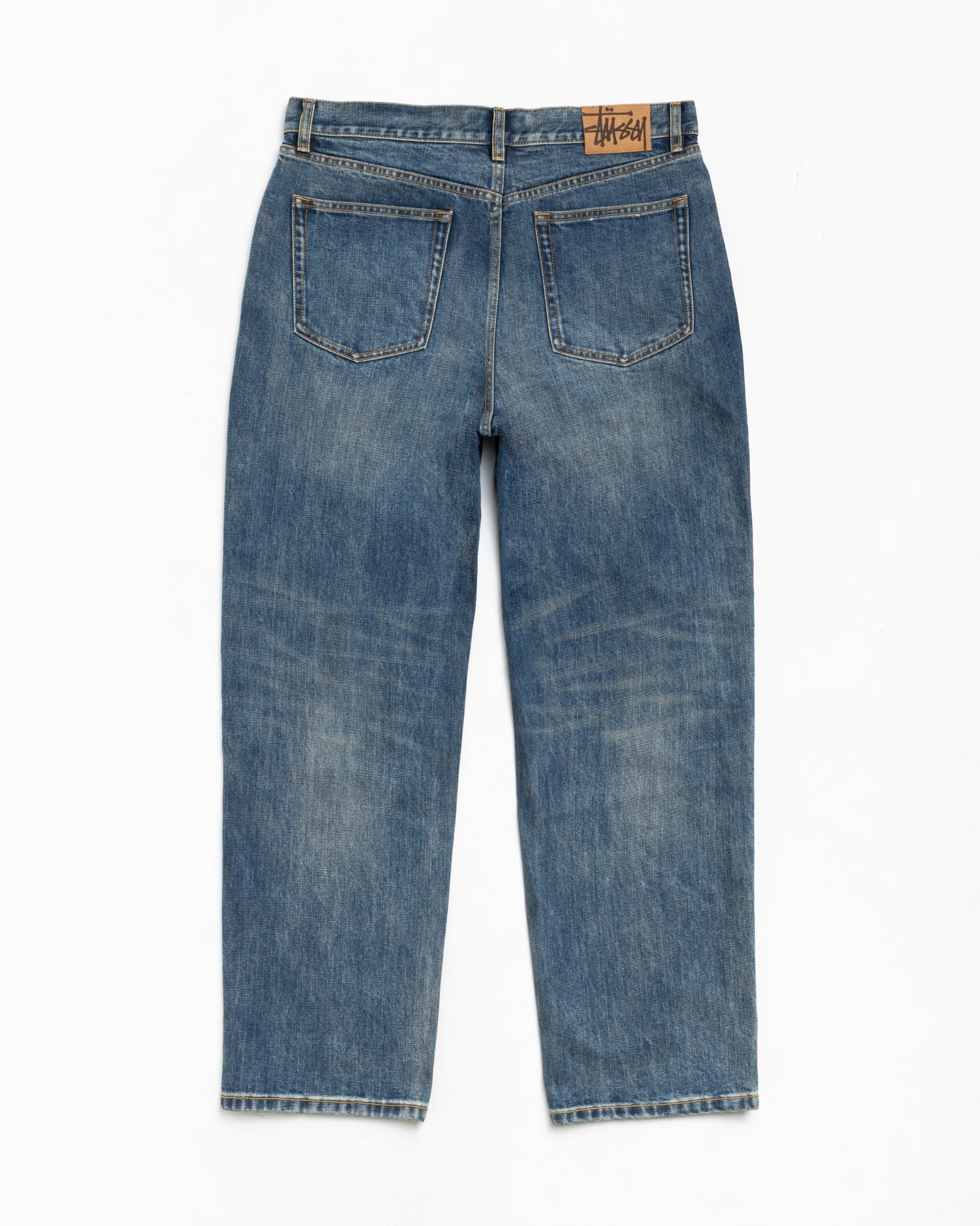 Faded blue denim jeans, back view with two patch pockets and leather logo waistband patch