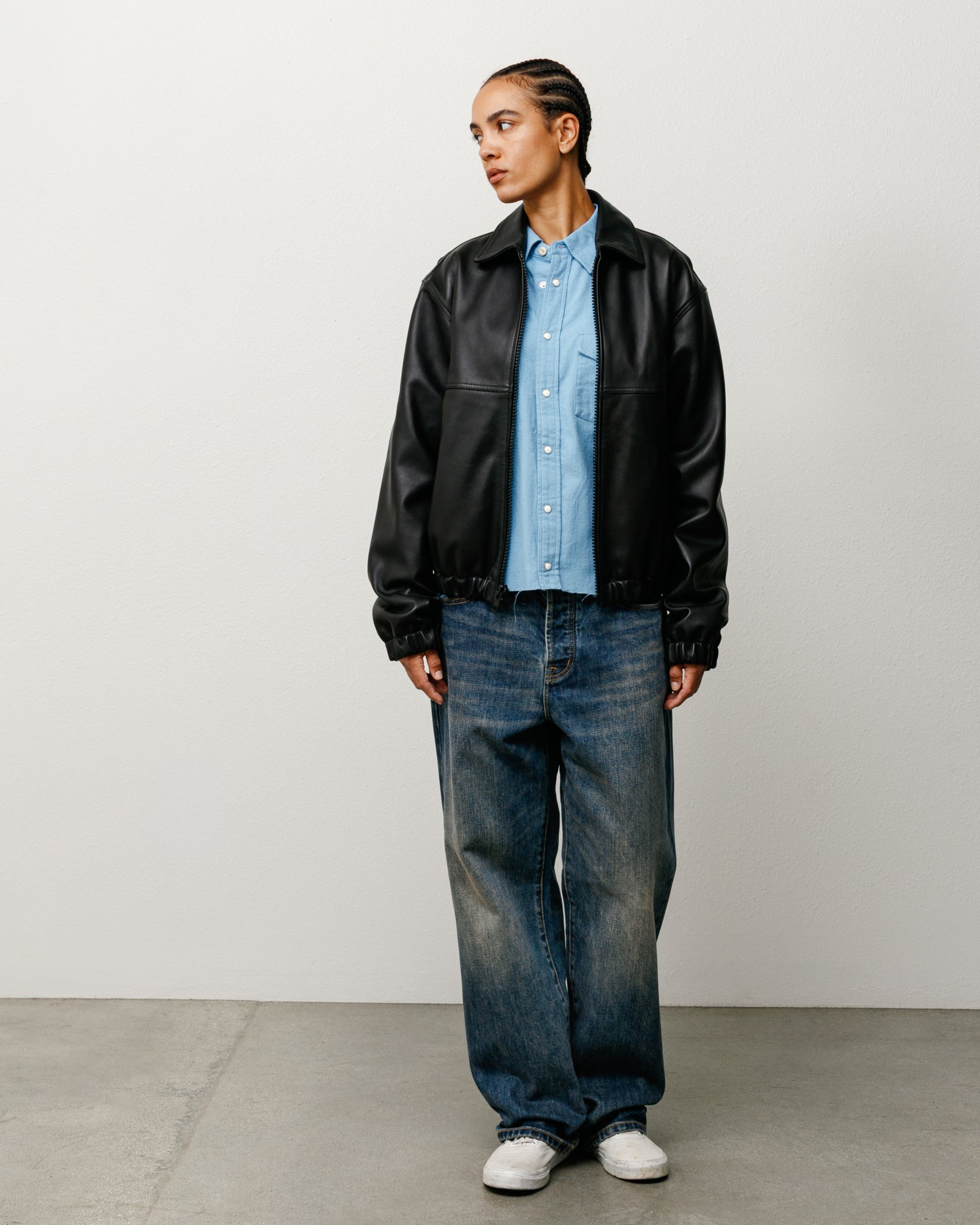 Model wears blue slub denim baggy jeans with relaxed rise and a worn-in wash, styled with sneakers.