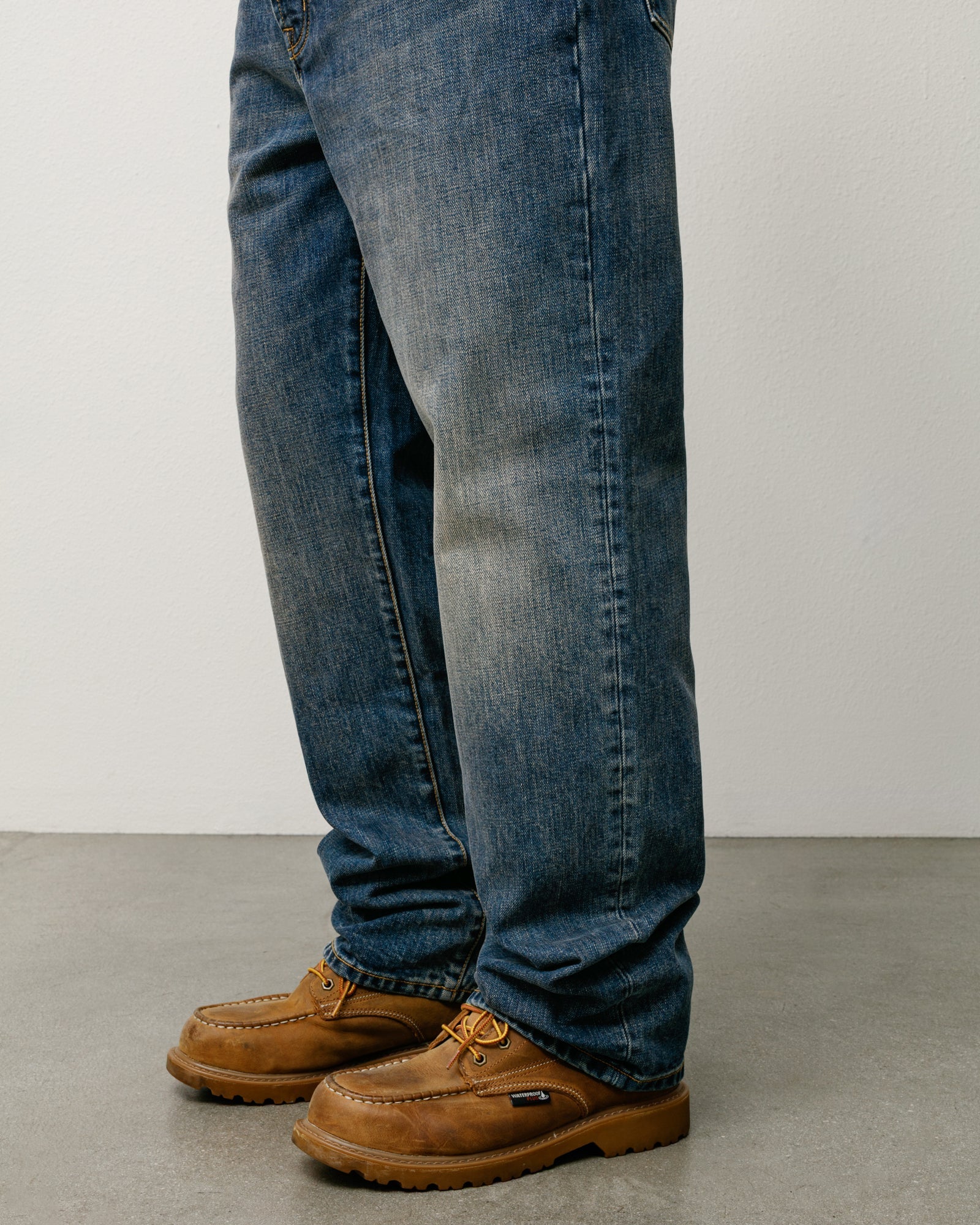 Blue slub denim straight-fit jeans on model, paired with tan moc‑toe boots.