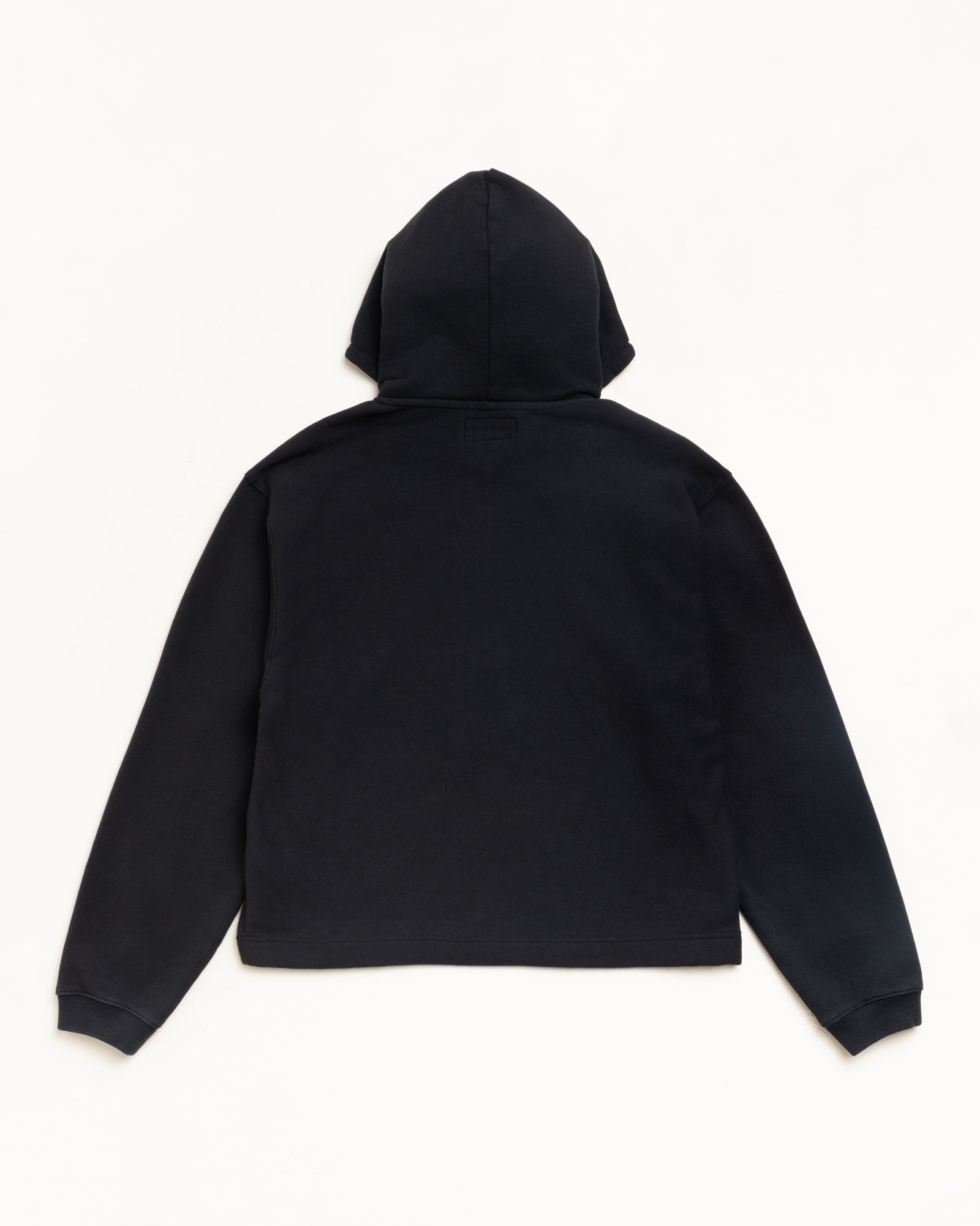 Black fleece pullover hoodie, back view with attached hood and ribbed cuffs