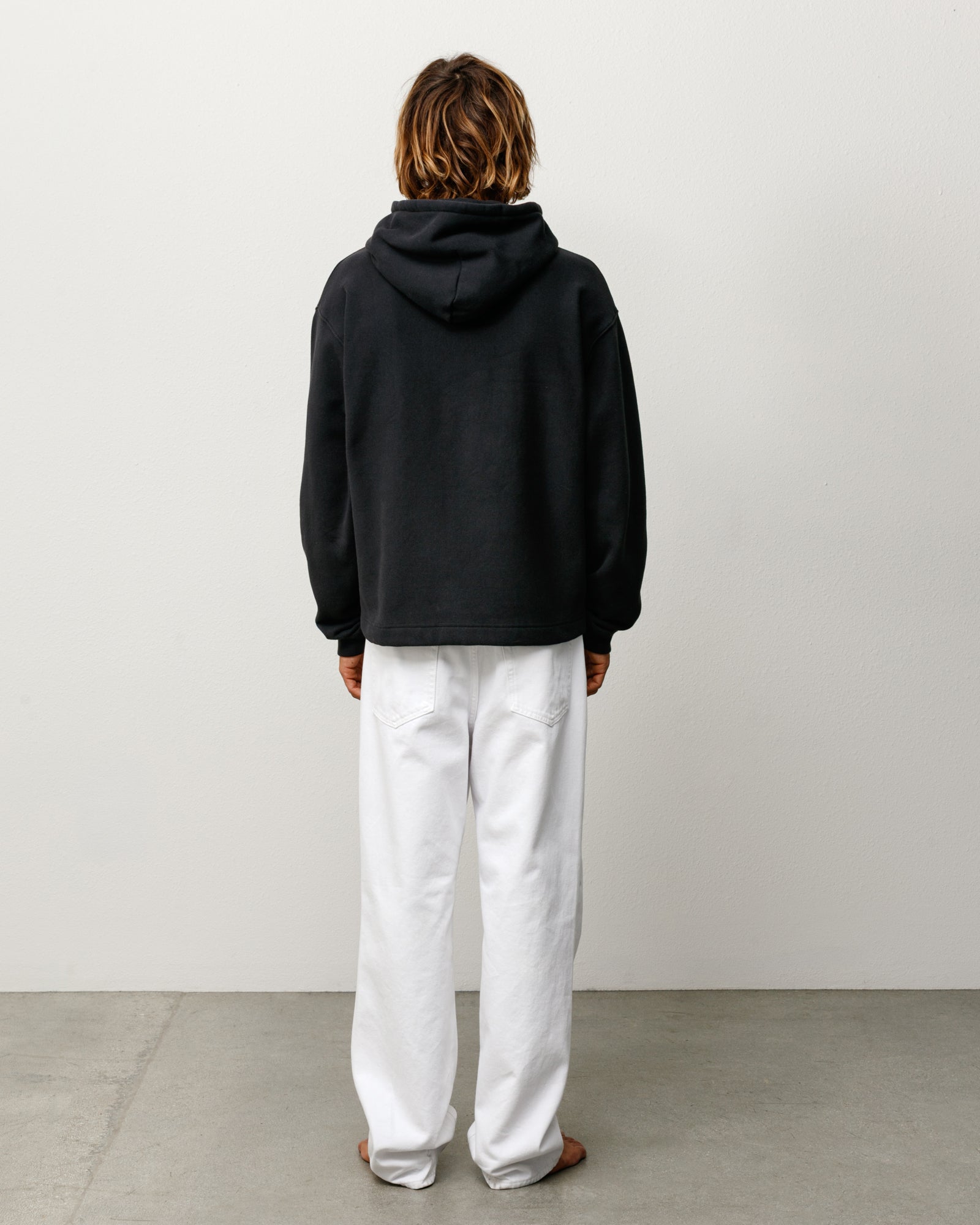 Back view of black pullover hoodie, unisex long sleeve sweatshirt with relaxed fit