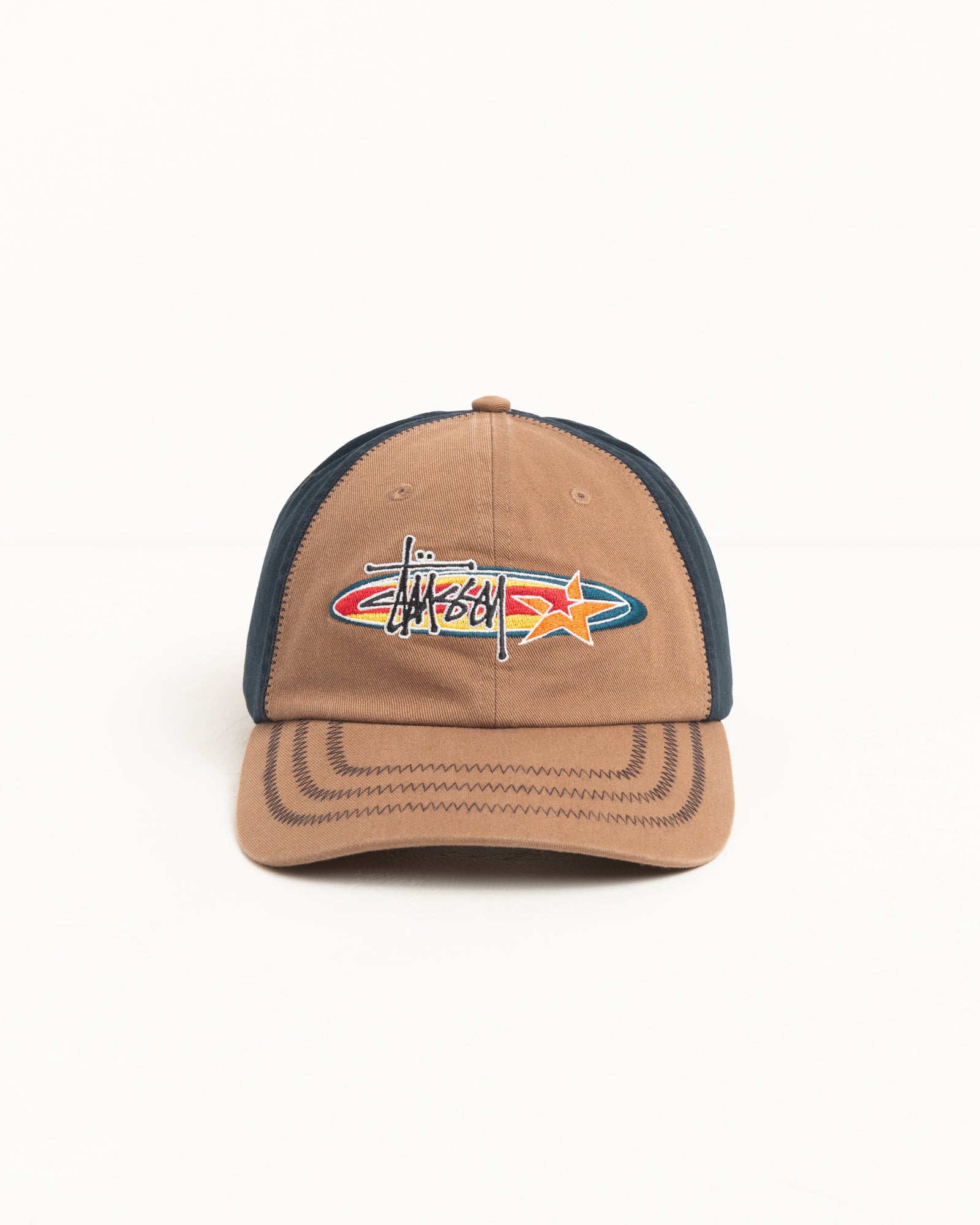 Brown low-profile cap with multicolour oval star logo, contrast navy side panels, and zig-zag brim stitching