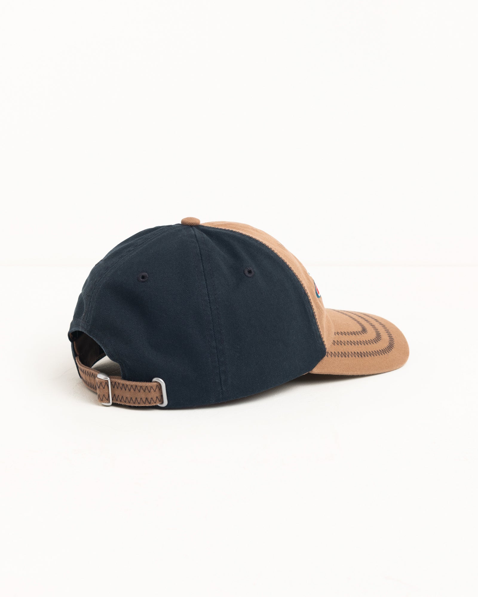 Two-tone brown and navy cotton twill cap, rear view showing strapback closure and metal slider.