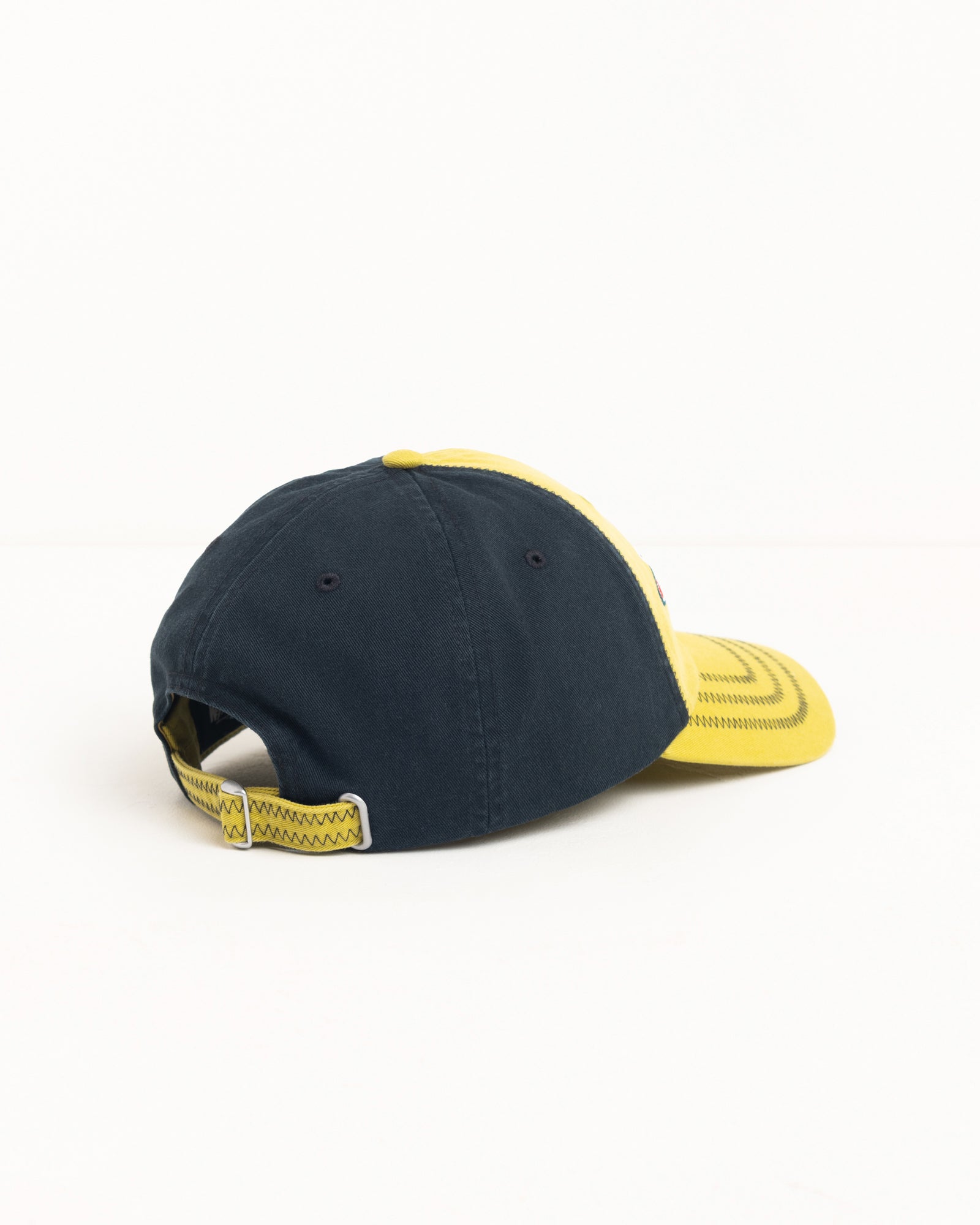 Two-tone lime and navy cotton twill strapback cap with zig-zag stitching and curved brim.