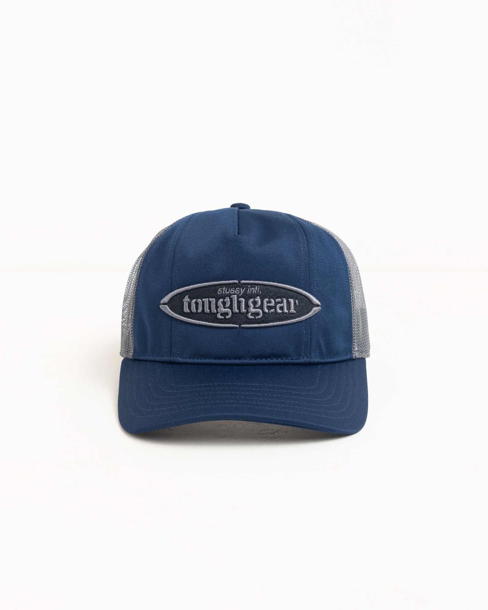 Navy trucker cap with mesh back and raised oval logo patch; precurved brim, unisex.