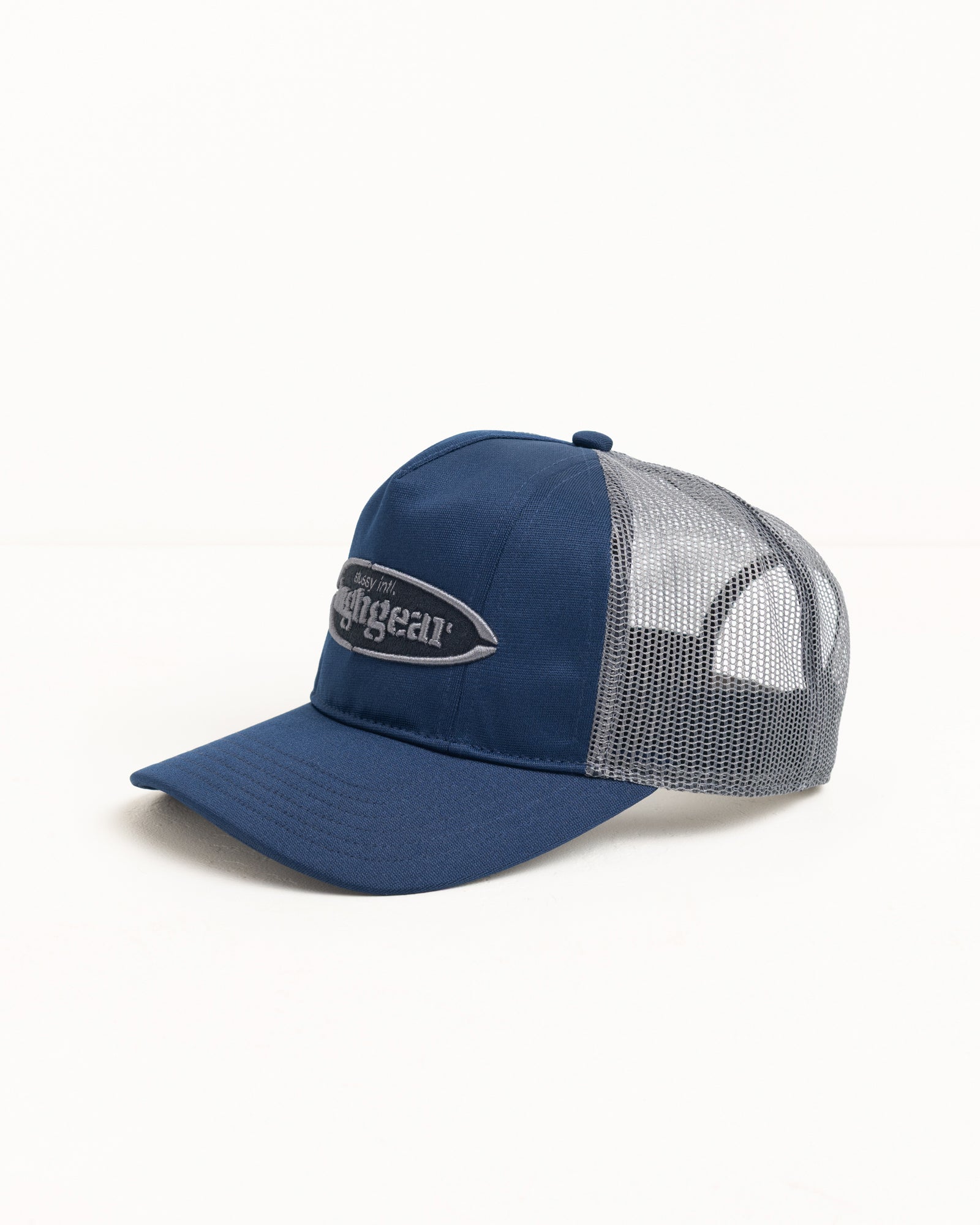 Navy trucker cap with grey mesh back and raised oval logo patch, precurved brim