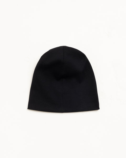 Black cotton jersey skullcap beanie, flat lay on a white background
