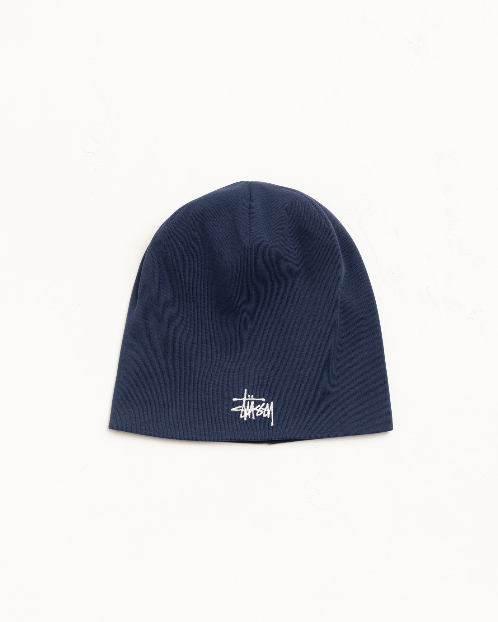 Navy jersey skullcap beanie with white logo embroidery, fitted unisex style
