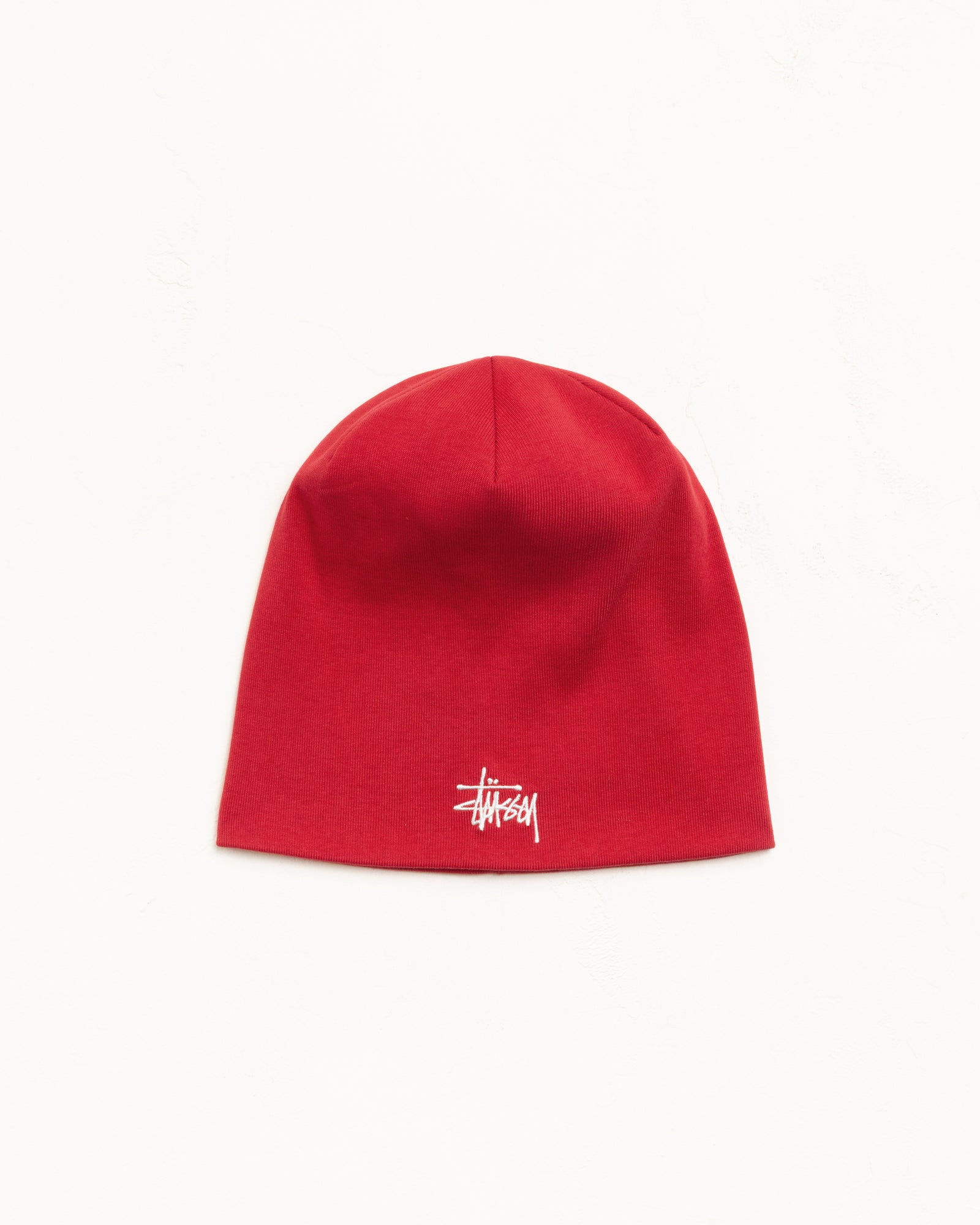Red cotton jersey skullcap beanie with white embroidered logo, unisex fit.