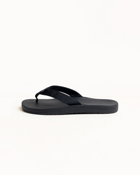 Black rubber flip-flop with wide fabric straps and textured sole, side profile