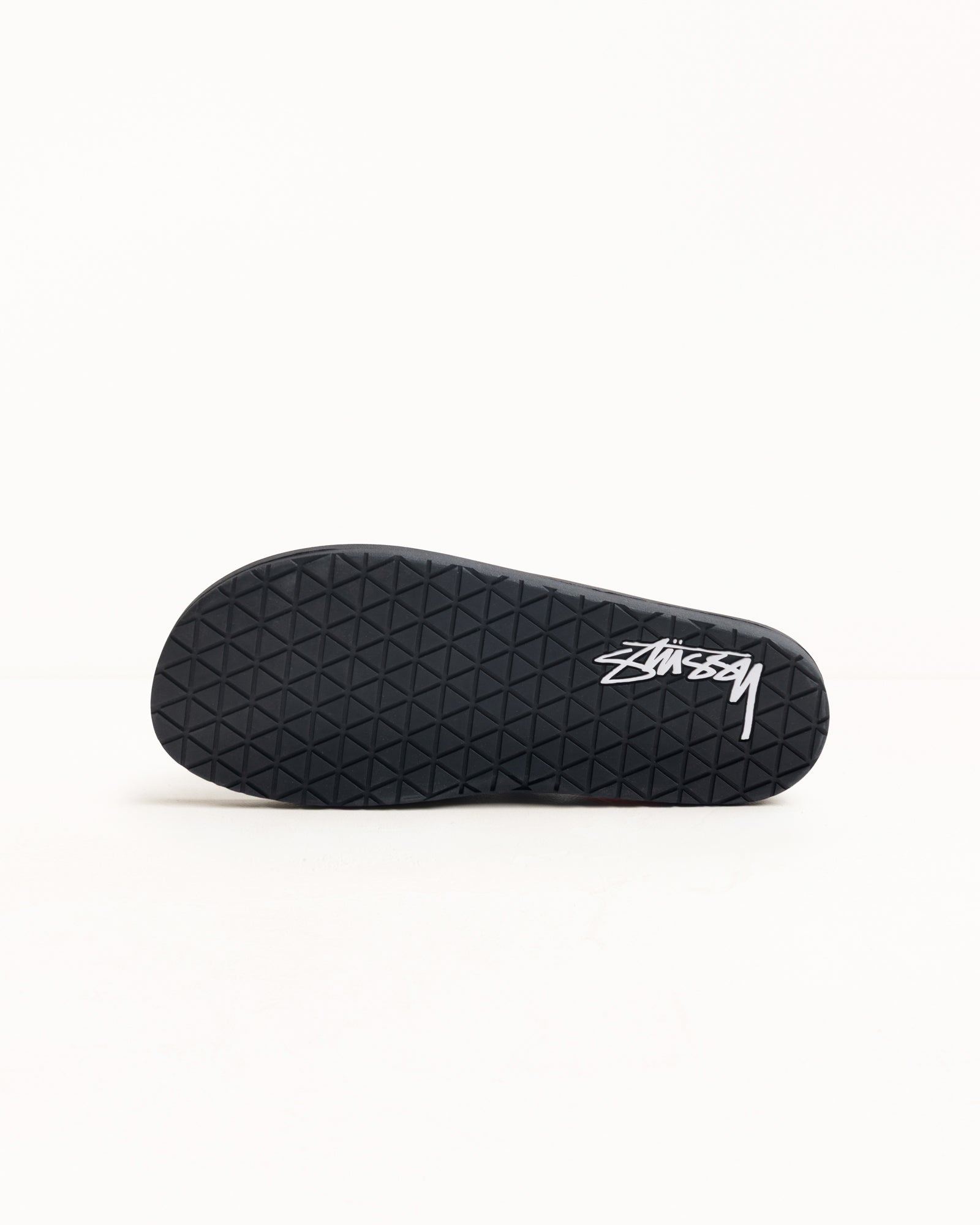 Black rubber flip-flop outsole view with diamond tread and white logo